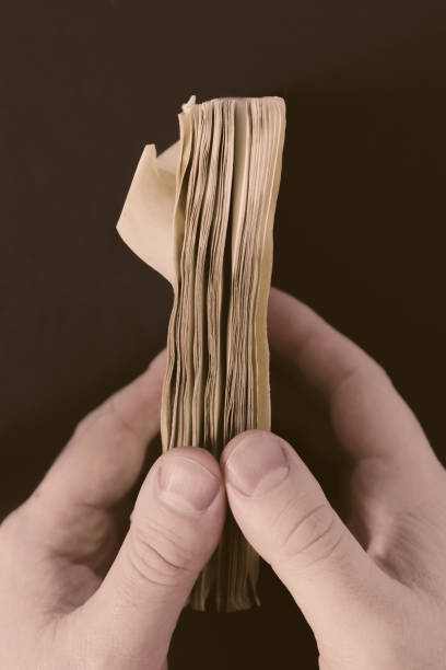 istock Closeup vertical shot of a man's hand opening an old weathered paper diary notebook 1440553594