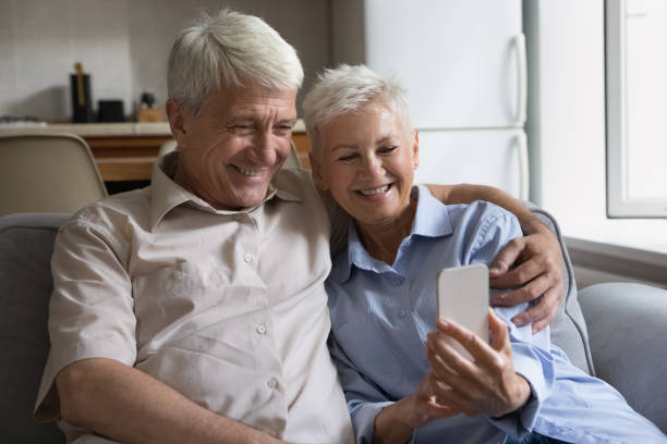 istock Senior couple using modern smartphone seated on sofa at home 1440554594