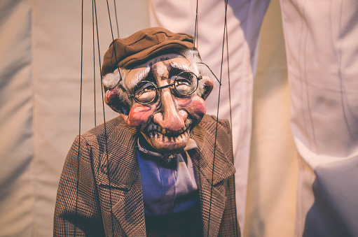 A marionette doll of an old man controlled by strings