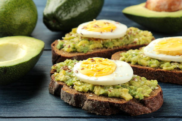 istock Sandwich with avocado puree and egg on a blue wooden table. close-up 1440555405