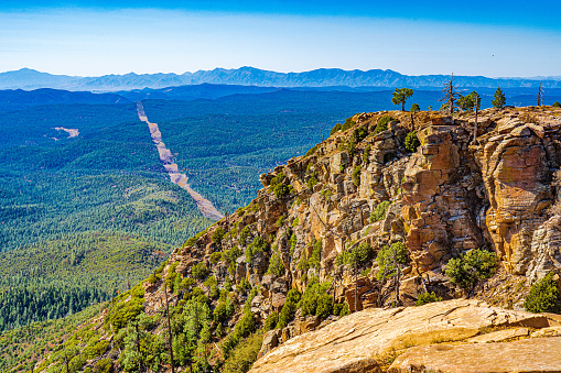 The view is looking over the edge of the Mogollon Rim in Arizona to the forest below and the mountains beyond