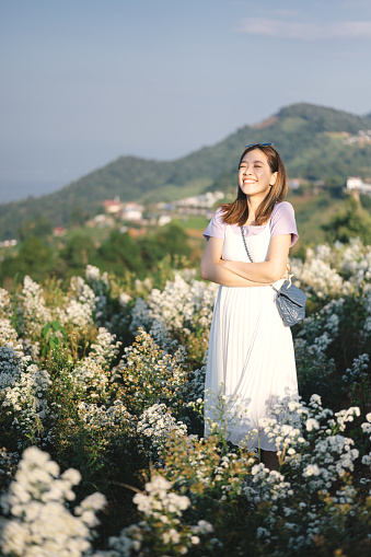 Young asian woman in white dress enjoying margaret flower blooming around she in mon jam chiang mai north of thailand