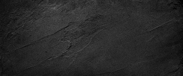 istock Black or dark gray rough grainy sand texture background 1440556314