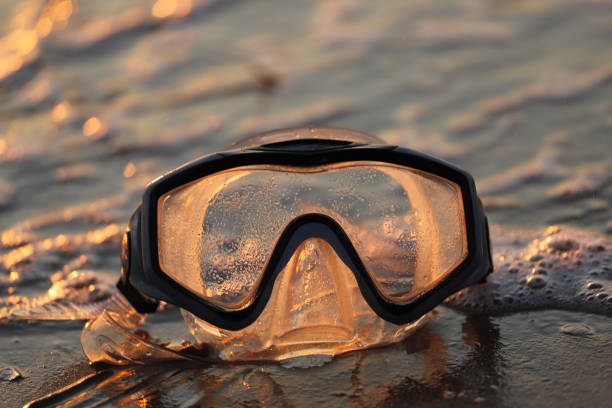 A selective focus shot of a diving goggle mask on a seashore