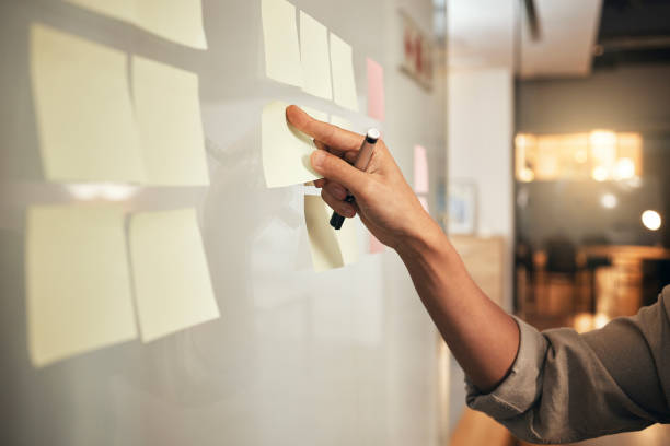 istock Planning, brainstorming and sticky note in business hand for workflow management, strategy planner and ideas on glass wall board. Creative, innovation and mission of a startup company writing notes 1440556695