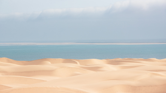 A beautiful shot of smooth sandy dunes near blue water