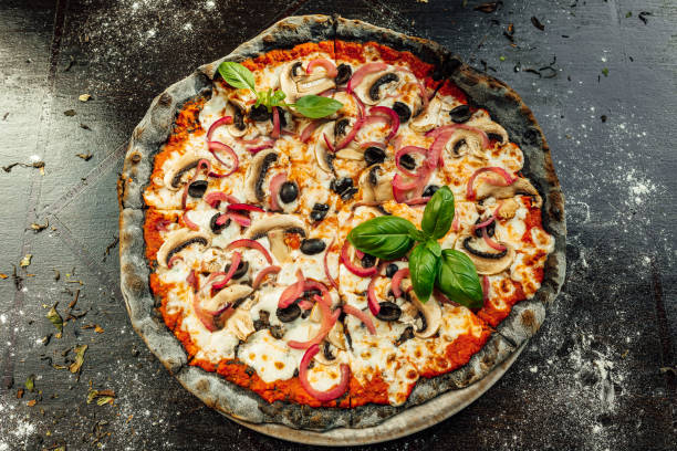 istock Top view of appetizing pizza with black dough and various vegetables 1440556955