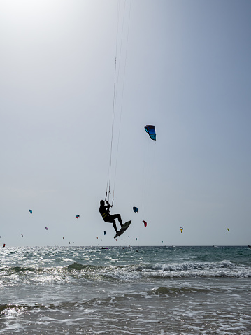 Unrecognizable flying with his kitesurf. In the background unrecognizable kite surfing.