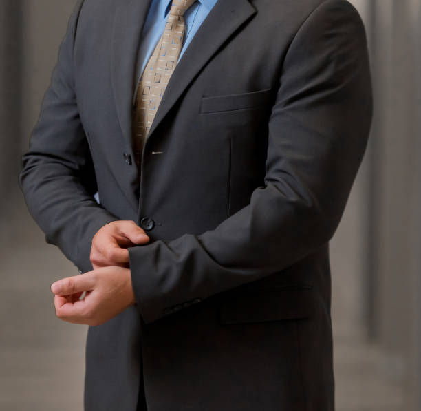 istock Good-looking unrecognizable man wearing a black suit and a tie, and posing in a room 1440557122