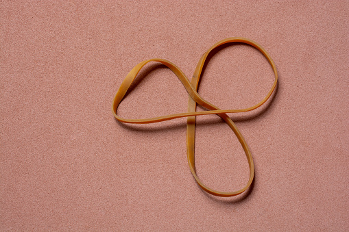a smallyellow rubber belt forming three circles on a pink background