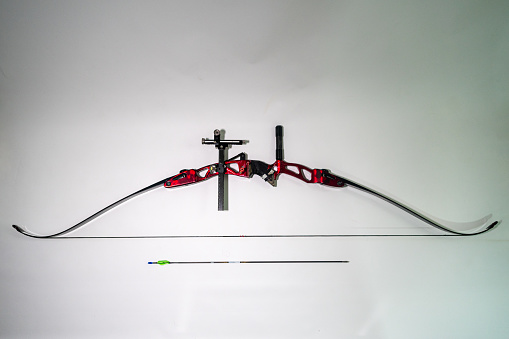 A top view of a bow with a single arrow placed on a white surface