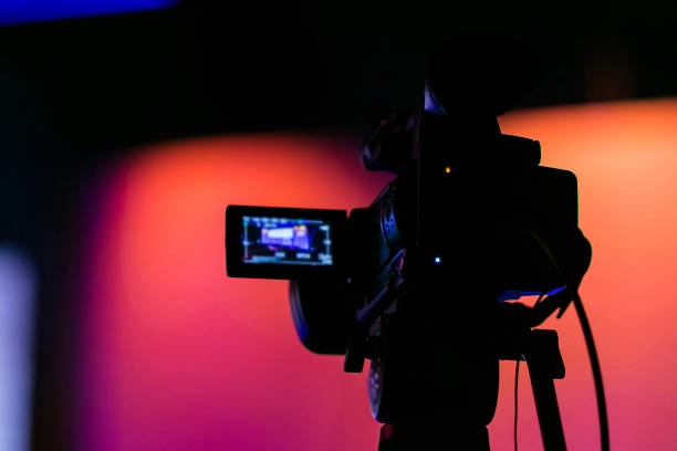 istock Selective focus of a professional video camera on blurred orange and pink shaded background 1440559933