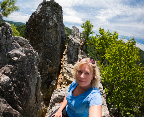 Blond female talks a selfie while hiking the summit fin atop Seneca Rocks, West Virginia. USA