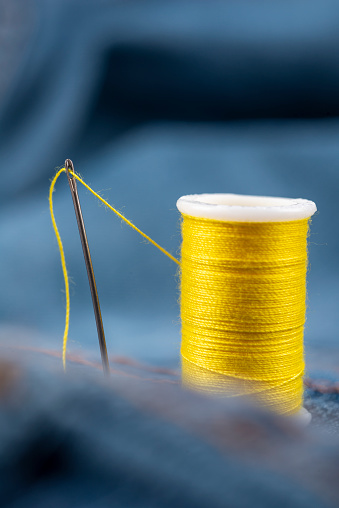 Multi-colored threads on bobbins, needles and pins, sewing kit.