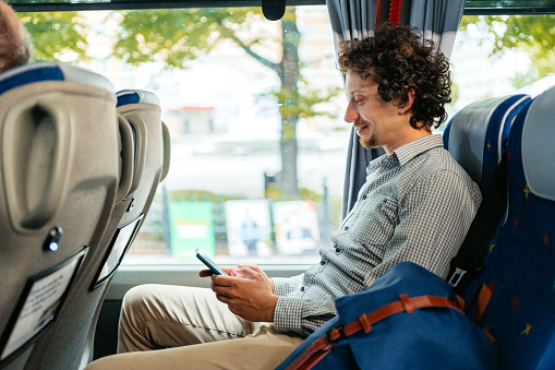 Handsome young man using his smart phone in the bus, while traveling in Stockholm, Sweden.