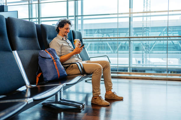 joven usando un teléfono inteligente y bebiendo café en el aeropuerto de estocolmo - airport waiting room waiting airport lounge fotografías e imágenes de stock