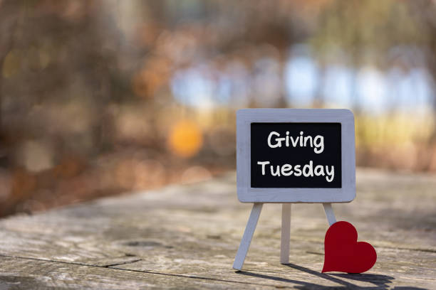 Giving Tuesday text message on chalkboard easel soft bokeh background copy space stock photo