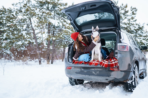 Young woman and cute husky dog enjoying outdoors into the car. Travel concept. Winter season.