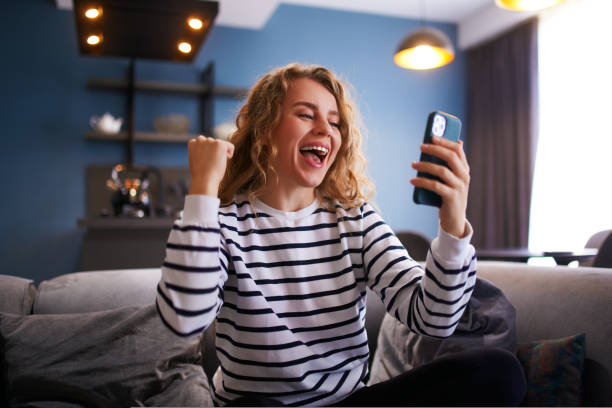 Female rejoice, celebrate a prize, big lottery win, auction victory, profitable bet on crypto stock market. Woman checks e-mail, news about success on smartphone or cellphone. stock photo