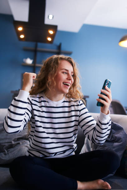Female rejoice, celebrate bank loan acception, big lottery win, auction victory, profitable bet on crypto stock market. Woman checks e-mail, news about success on smartphone or cellphone. stock photo