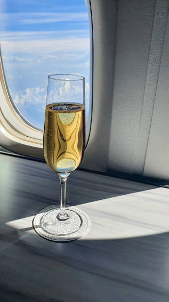 bicchiere di champagne in flute sul tavolo nella cabina dell'aeromobile vicino al finestrino dell'aereo. concetto di viaggio di lusso, volo in business class - commercial airplane finance airplane private airplane foto e immagini stock