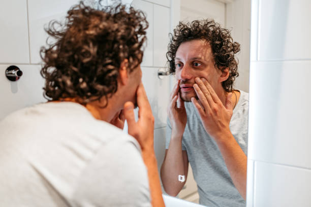 istock Young Man Looking At Himself In The Bathroom Mirror 1440570520