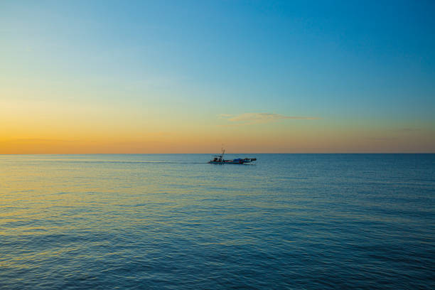 mar y pequeños barcos de pesca por la mañana,un pequeño barco de pesca en medio del mar al atardecer - retro fish day sunset sunlight fotografías e imágenes de stock