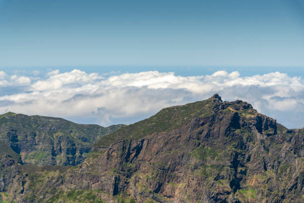 Madeira mountain range with white clouds behind it.