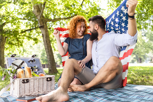 Young couple on picnic holding American flag