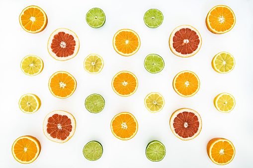 Halved multicolored citrus fruits artfully arranged on a white background
