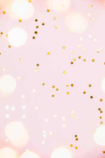 Christmas festive background. Gold party decorations, confetti stars, christmas lights on pastel pink background. Christmas, winter holiday, new year concept. Flat lay, top view, copy space. stock photo