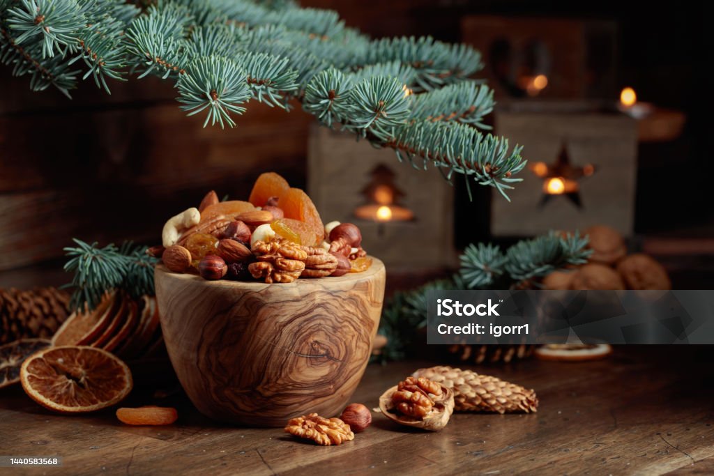 Dried fruits and assorted nuts on an old wooden table. Dried fruits and assorted nuts on an old wooden table. Christmas still-life with spruce branches and burning candles in old lanterns. Nut - Food Stock Photo