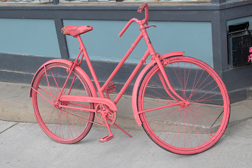 Older bicycle crudely painted pink on street sidewalk in Santa Fe, New Mexico USA