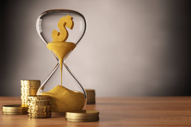 istock Dollar Melting Concept with Hour Glass and Coins 1440586528