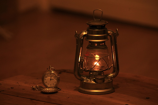 sailor's lantern and pocket watch on wooden table