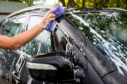 Young man washing his car at a jet car wash