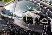 Outdoor car wash. Gentle Car Washing. Modern Car Covered by soap and Water. automobile, auto wash foam water,Auto detailing or valeting concept. Selective focus.