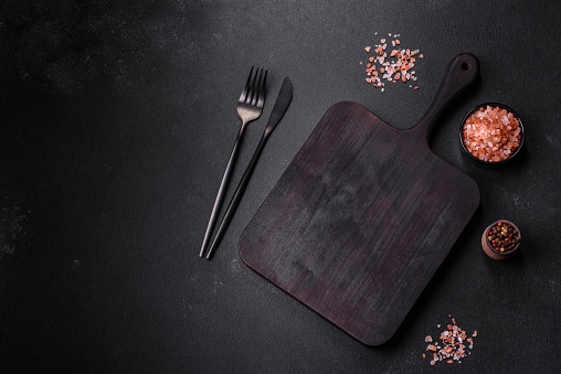 Wooden cutting board with kitchen appliances on a black concrete background. Cooking at home