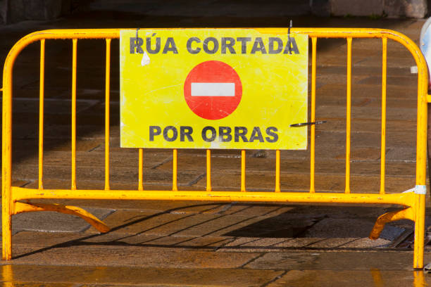 Street closed sign hanging from yellow portable metal fence. Pedestrian zone, Santiago de Compostela, Galicia, Spain.