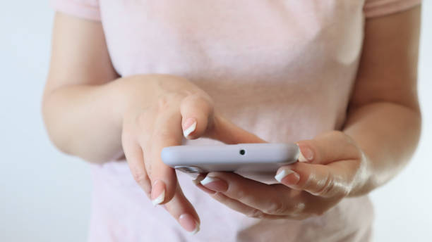 istock Woman hand using smartphone on light background. Woman using a Phone, close up view. 1440604226