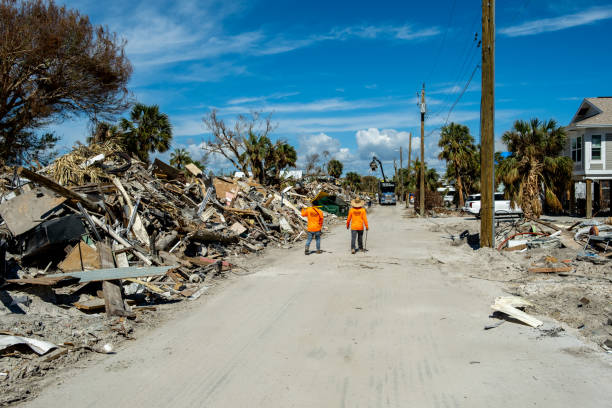 trabajadores caminando a lo largo de montones de escombros cerca de estero blvd - hurricane ian fotografías e imágenes de stock