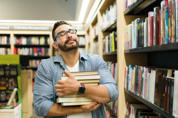 lector alegre que se siente feliz comprando muchos libros - mid adult men smart casual white happiness fotografías e imágenes de stock