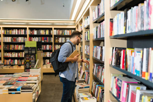 istock Caucasian man with a backpack browsing the bookshelves at the store 1440606870