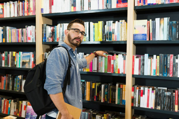 istock Caucasian man at the bookstore looking at the camera while choosing a book 1440606885