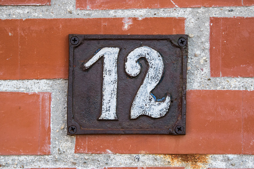 Old retro weathered cast iron plate with number 12 closeup
