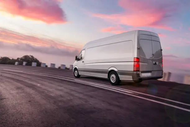 Photo of grey colored van driving fast on freeway for overnight express dilevery