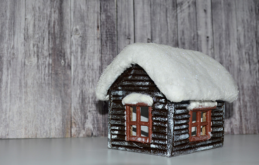 a small wooden decorative house hut with a snow-covered roof and windows. toy for decorating a room or home for Christmas or New Year holidays