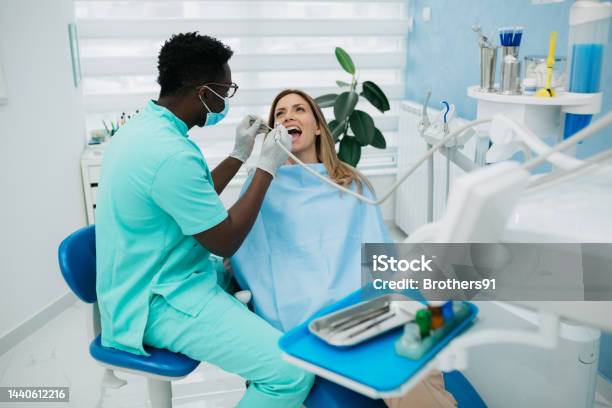 A Professional Dentist Carefully Working With His Female Patient Stock Photo - Download Image Now