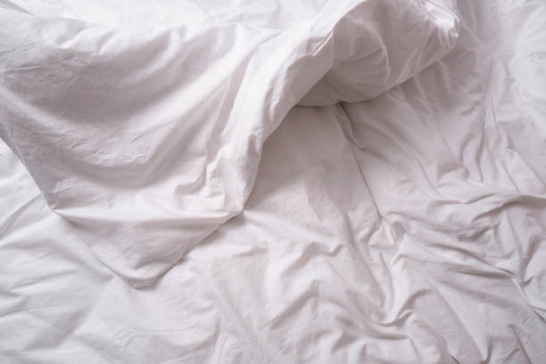 istock Top view of sheets and pillows. White linens. Bed texture 1440613290