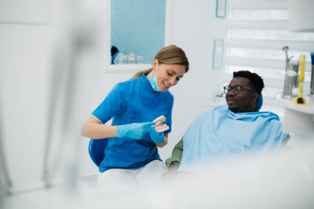 A professional female dentist with her male patient in her office stock photo
